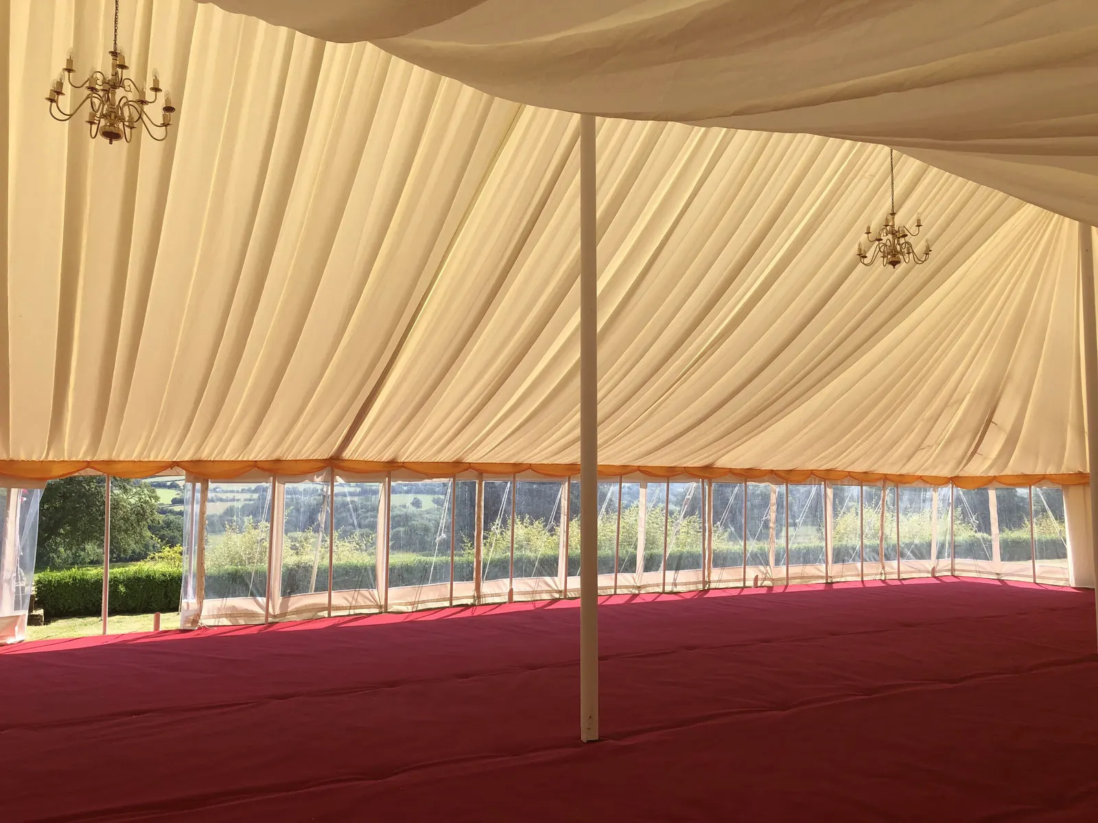 Pleated ivory lining inside a pole marquee with windows to the garden